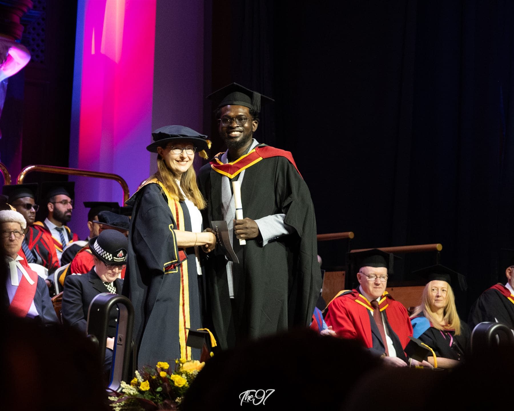 Àlọbọ̀ Travels graduate shaking hands as he receives his diploma